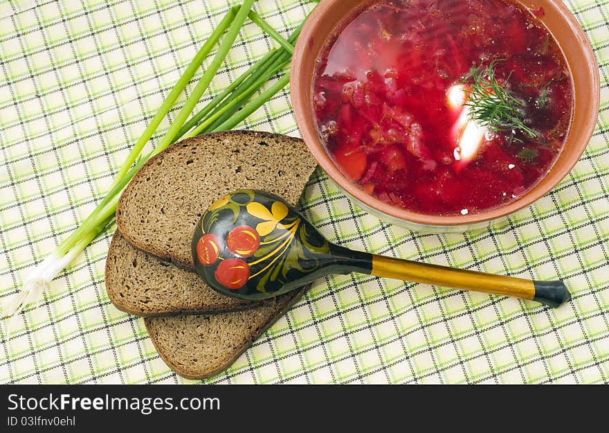 Bowl of a borsch with green onions and a wooden spoon in style Hohloma. Bowl of a borsch with green onions and a wooden spoon in style Hohloma