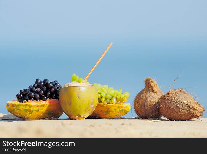 Papaya, coconut, nut and grapes on the sand. Papaya, coconut, nut and grapes on the sand