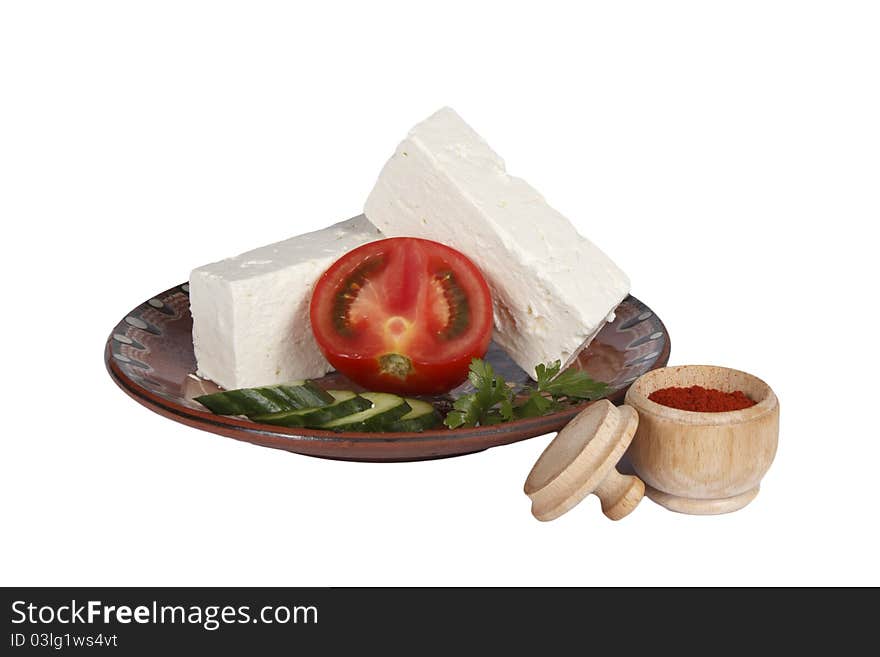 Bulgarian white cheese decorated with tomato and cucumber into a plate isolated on white. Bulgarian white cheese decorated with tomato and cucumber into a plate isolated on white