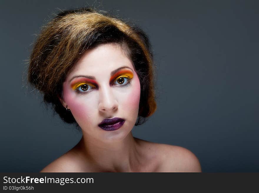 Beautiful young female against Grey with colourful make up