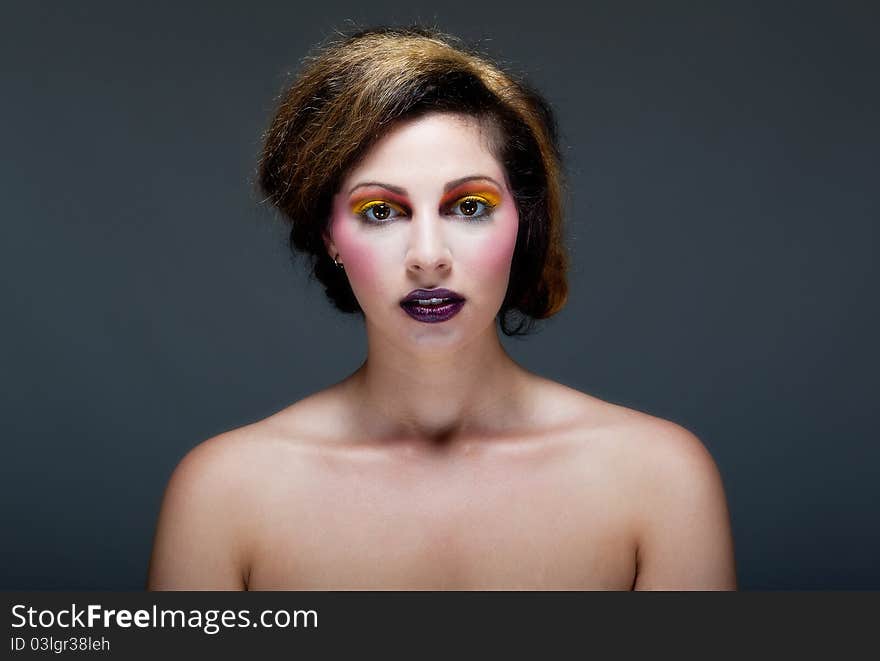 Beautiful young female against Grey with colourful make up