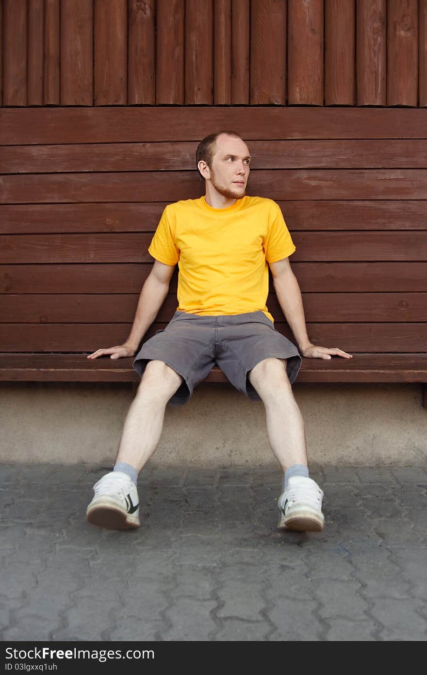 Man in yellow shirt sitting on bench