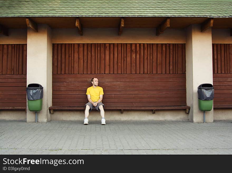 Man in yellow shirt sitting on bench