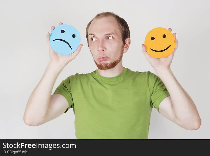 Young man in green shirt holding emotion smile symbols. Young man in green shirt holding emotion smile symbols