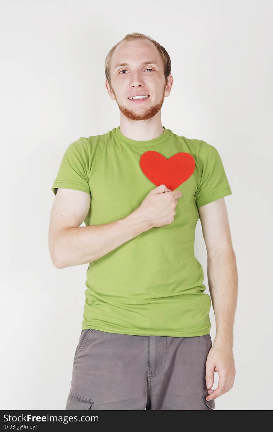 Young man in green shirt holding valentine heart card. Young man in green shirt holding valentine heart card