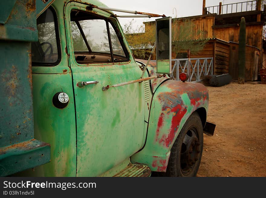 A Rusty old truck with patches of green and red paint in an old western town. A Rusty old truck with patches of green and red paint in an old western town