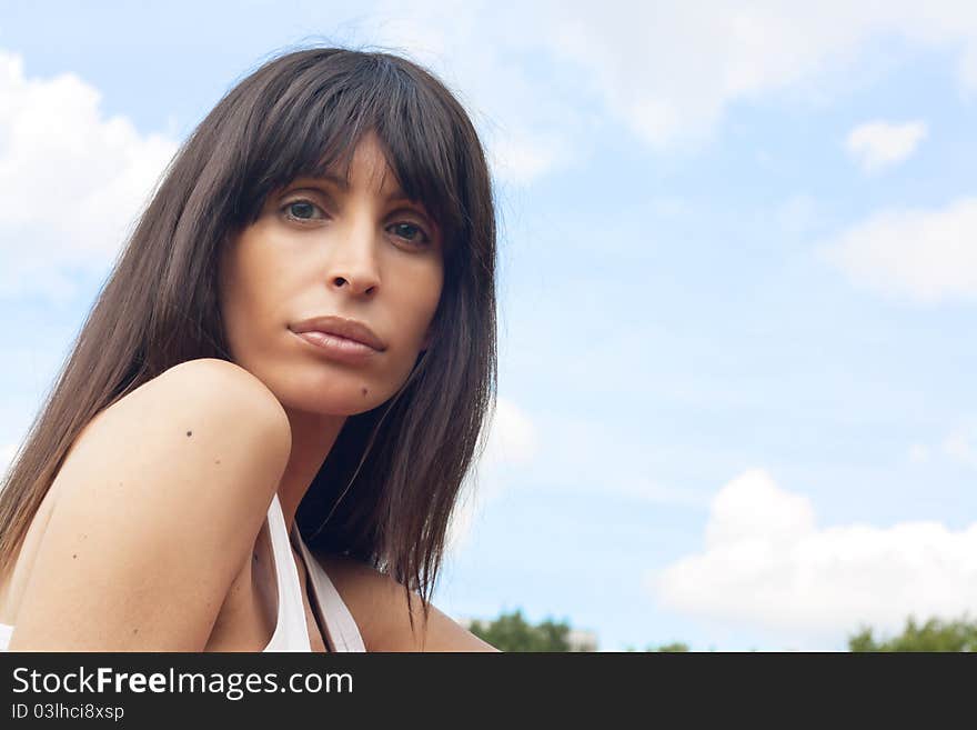 An attractive brunette in a park with the sky as a background. An attractive brunette in a park with the sky as a background.