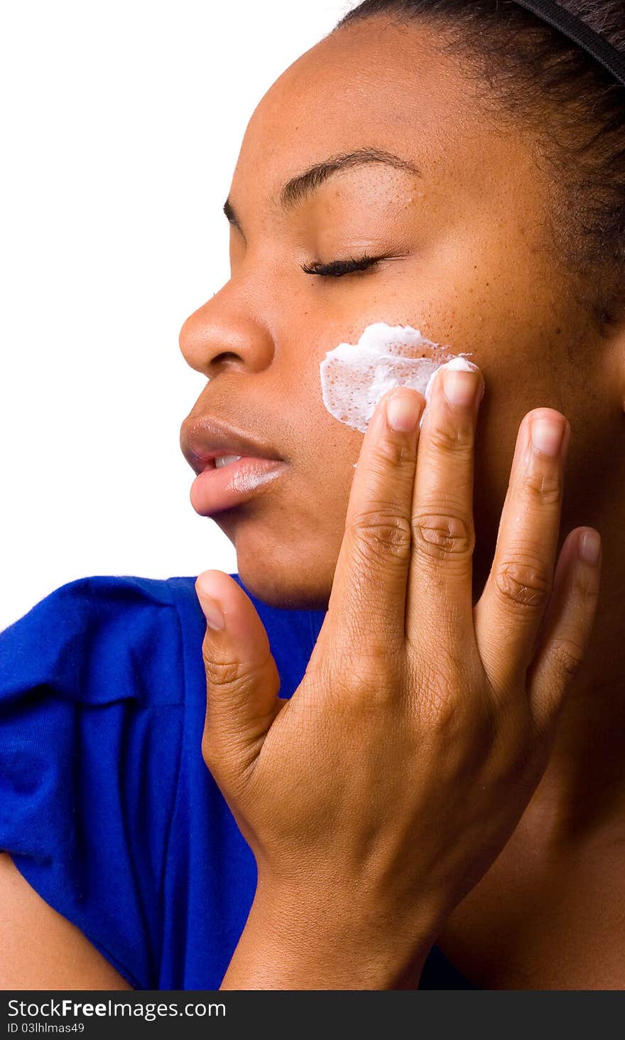 A young woman applying cream to her face. A young woman applying cream to her face.