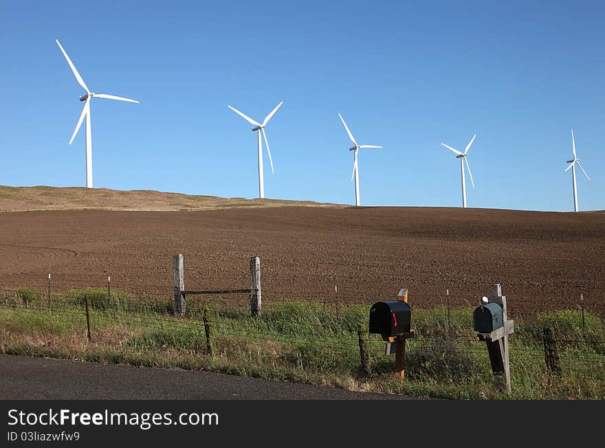 Mail boxes in rural countryside Washington state overshadowed by wind turbines in the background. Mail boxes in rural countryside Washington state overshadowed by wind turbines in the background.