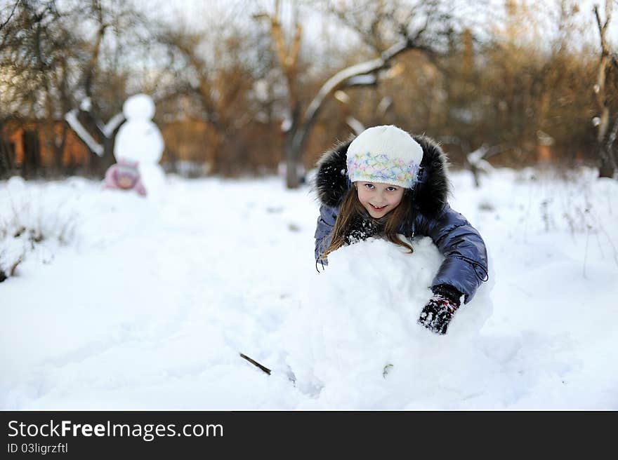 Little Girl rolling snow to make snowman