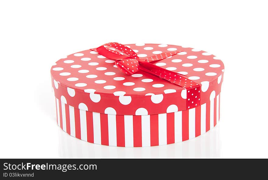 A red white dotted round cardbound box with stripes and a ribbon on top. A red white dotted round cardbound box with stripes and a ribbon on top