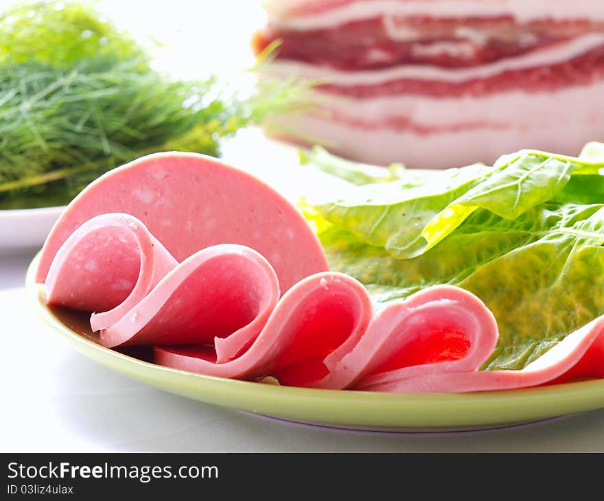 Sliced sausages on the background of a large piece of bacon