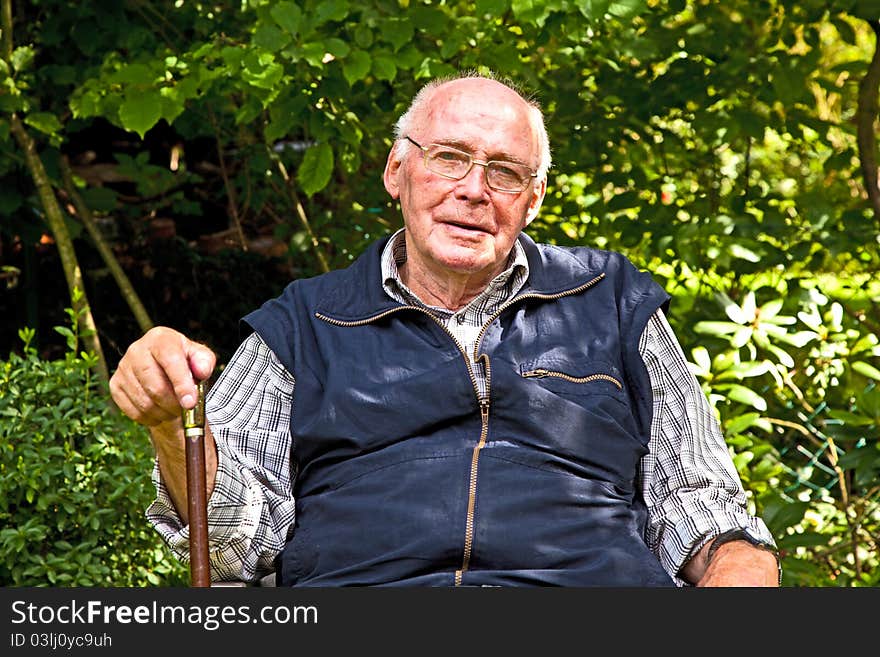 Portrait of elderly man sitting happy in his garden