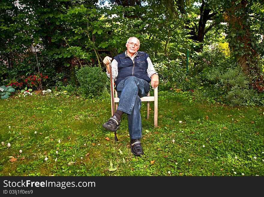 Portrait of elderly man sitting happy in his garden