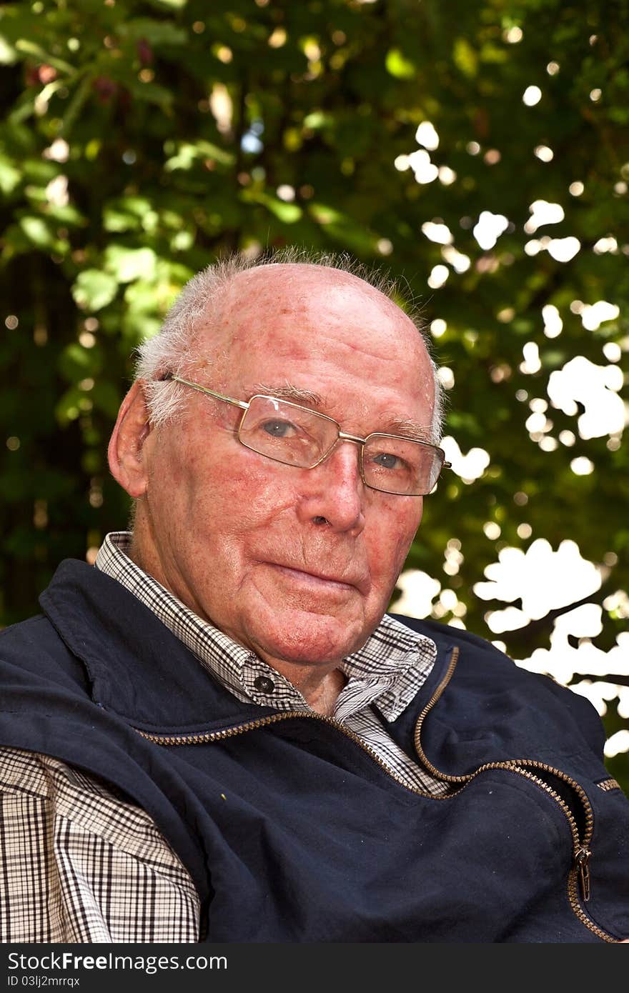 Portrait of elderly man sitting happy in his garden