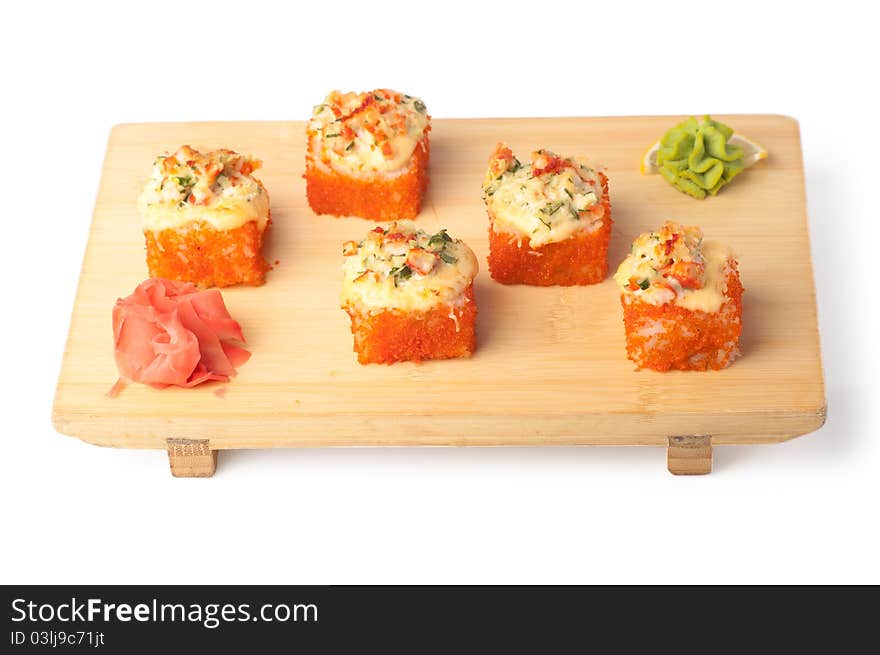 Wooden plate with four pieces of California rolls, wasabi and ginger