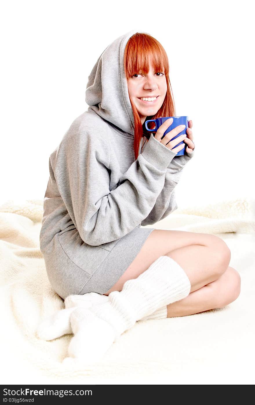 Young woman with cup of coffee sits on warm plaid on a white background.