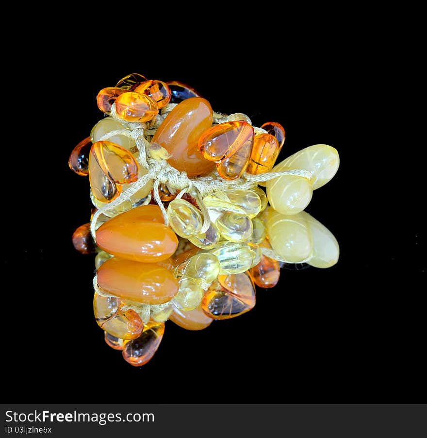 Bijouterie imitation jewelry of amber in the form of hearts with a mirror reflection on a black background