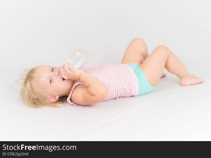 Baby eating milk from the bottle lie on floor