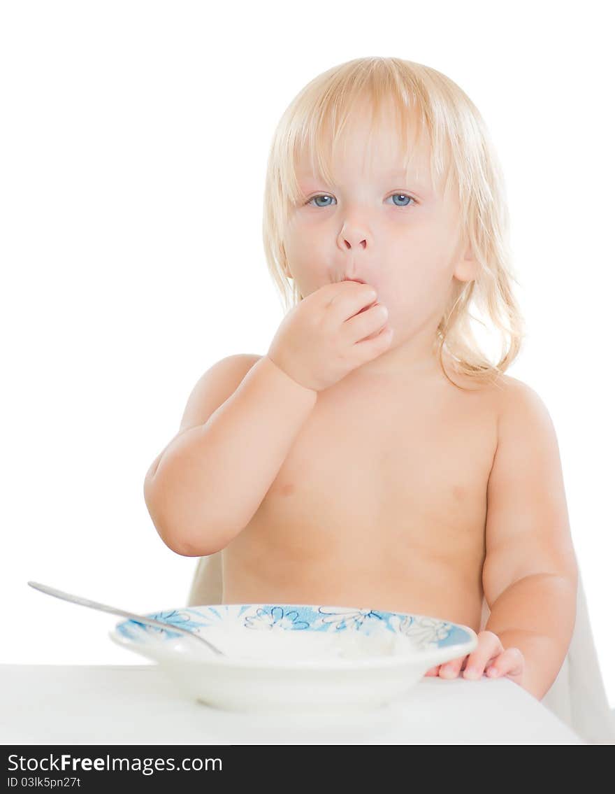 Adorable toddler girl eat porridge with spoon from plate