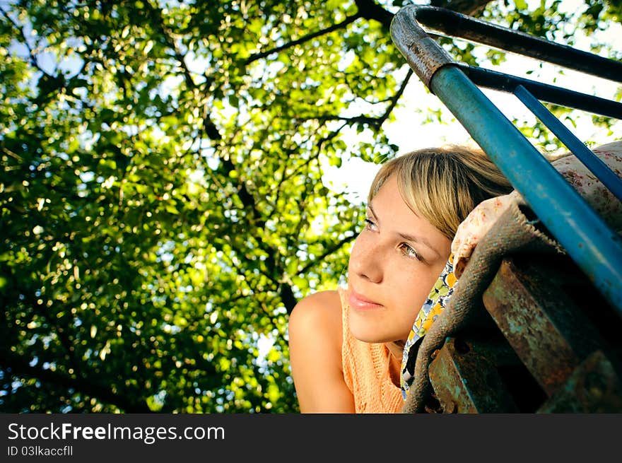 Young woman lying on a rusty bed outdoors. Young woman lying on a rusty bed outdoors