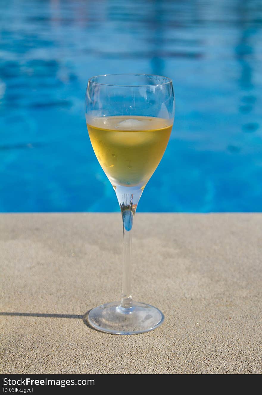 Glass of white wine next to the pool. Glass of white wine next to the pool