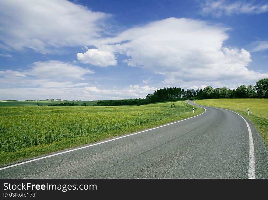 A deserted road crossing the green field. A deserted road crossing the green field.