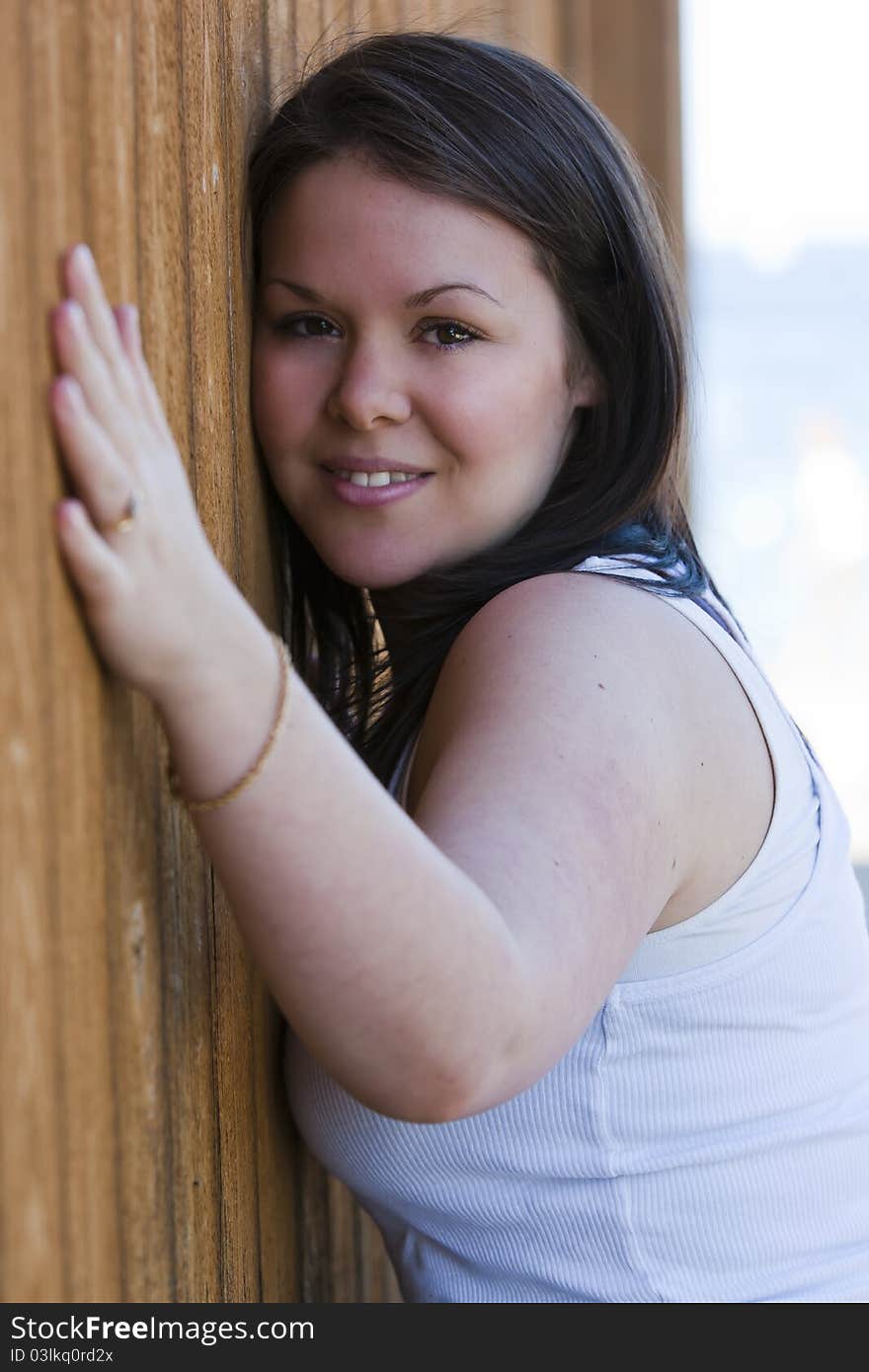 A beautiful young female leans against a wall. A beautiful young female leans against a wall