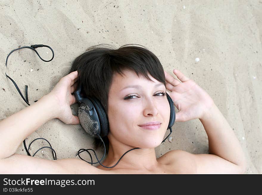 Young girl with ear-phones on the sand