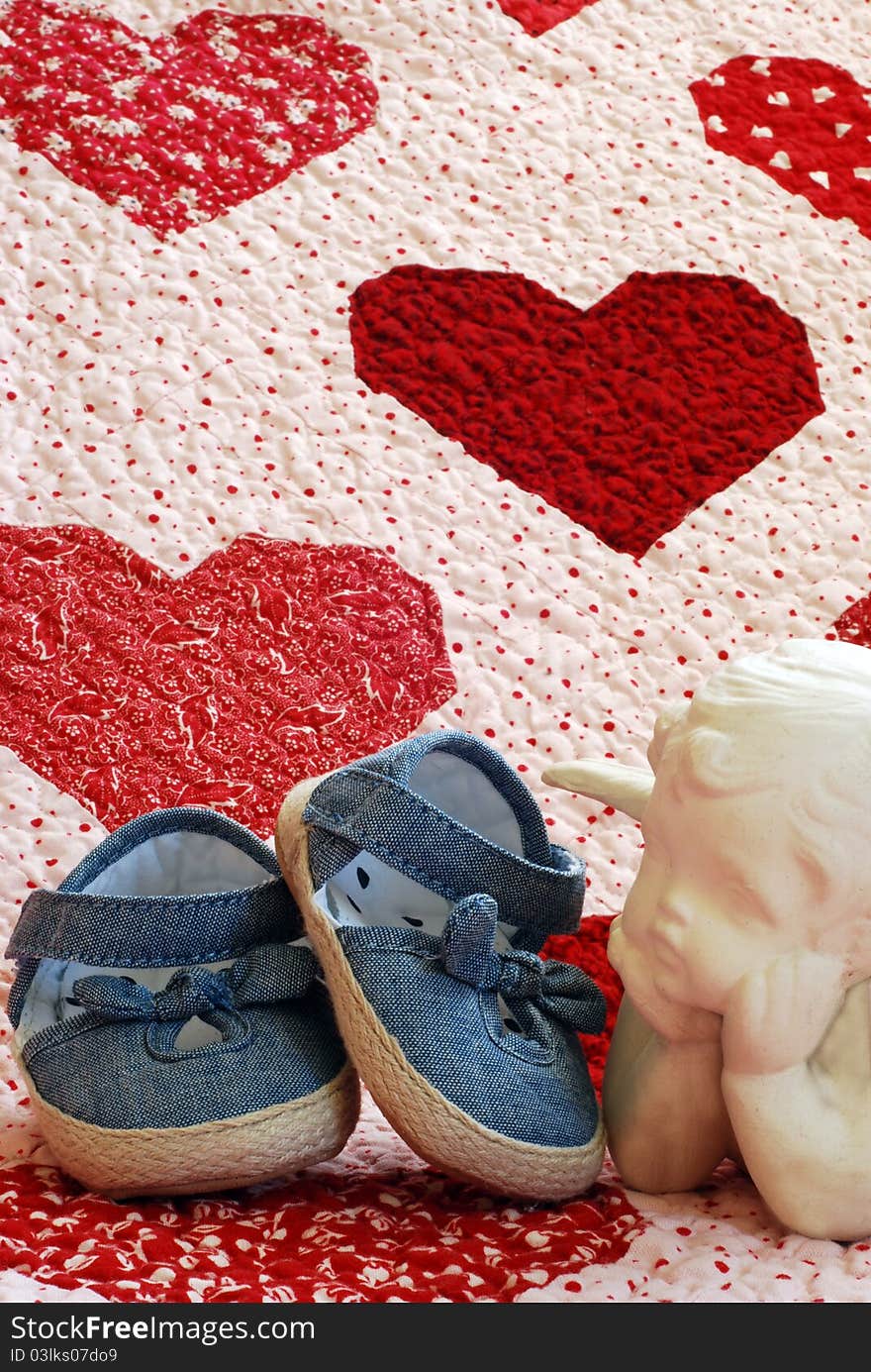 Denim shoes with ceramic angel on a quilt with red and white hearts  . Denim shoes with ceramic angel on a quilt with red and white hearts