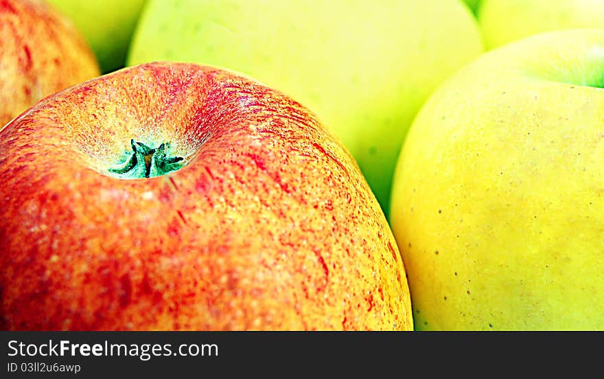 Red apple standing in front of large group of green apples. Red apple standing in front of large group of green apples