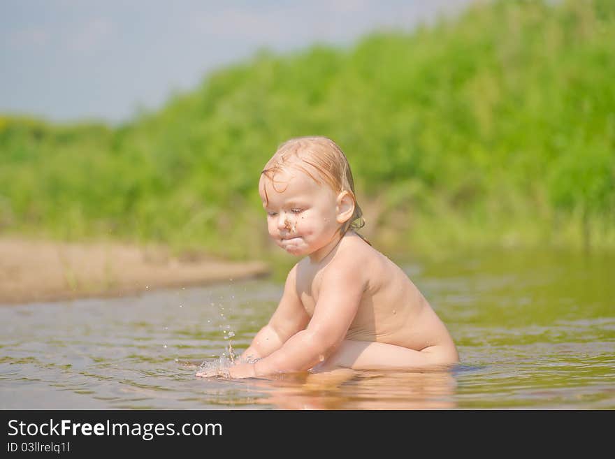 Adorable baby sit in river and play with sand