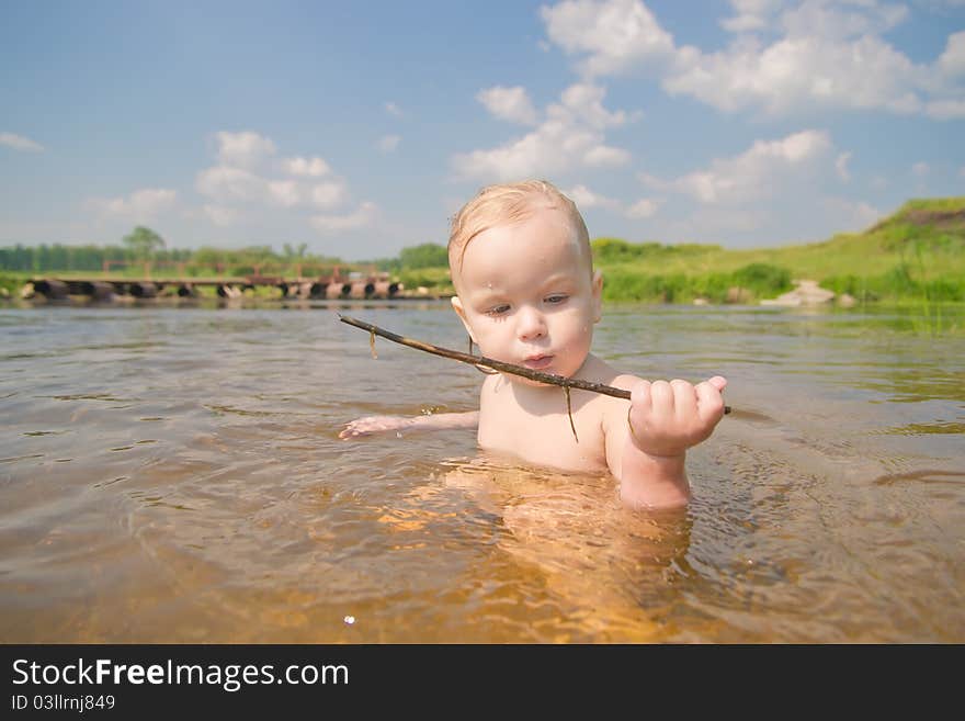 Adorable baby sit in river and play with wood