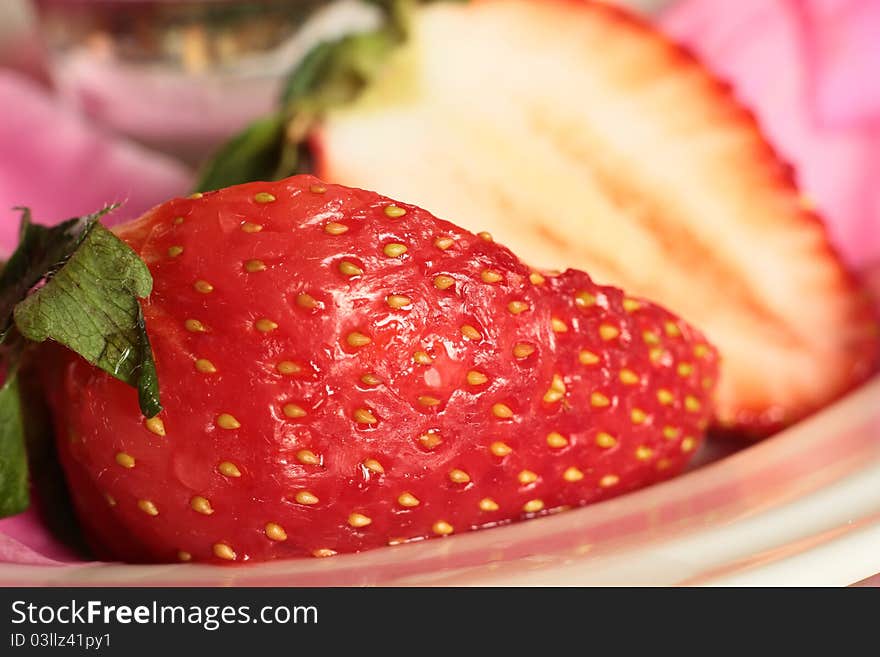 Image of a large tasty strawberry ready for eating on a pink and white plat. Image of a large tasty strawberry ready for eating on a pink and white plat