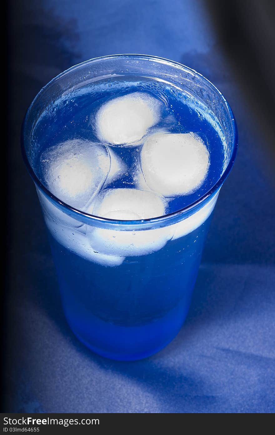 Blue glas of water with ice-cubes on a blue background. Blue glas of water with ice-cubes on a blue background