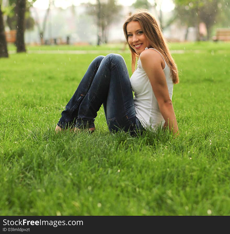 Cheerful woman in the park under the rain. Cheerful woman in the park under the rain