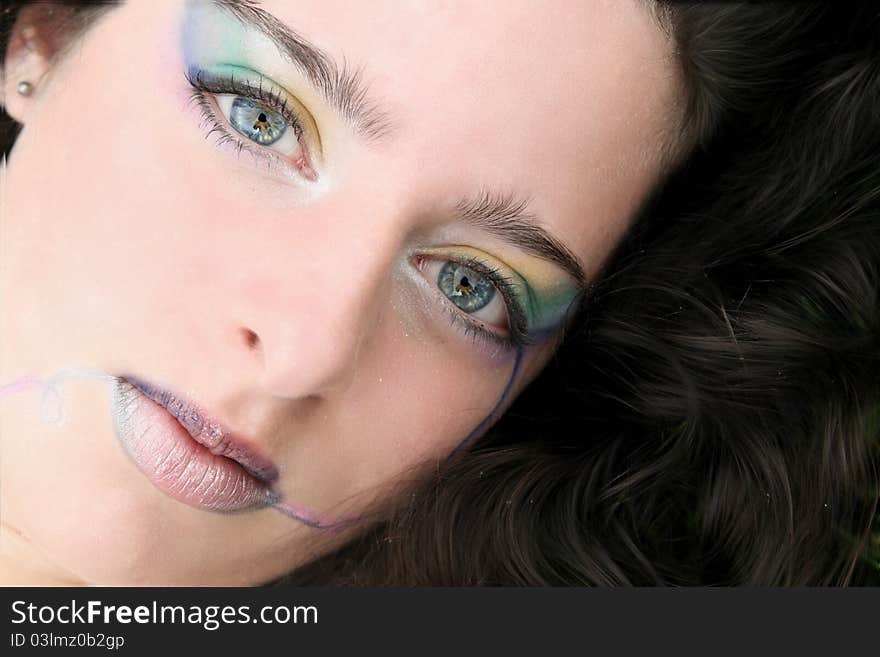 Close up of a young woman, hair surrounding her face, colorful makeup. Close up of a young woman, hair surrounding her face, colorful makeup.