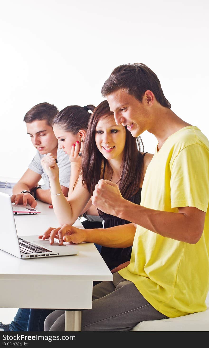 Young couple in front of laptop with others in the background. Candid picture. Young couple in front of laptop with others in the background. Candid picture.