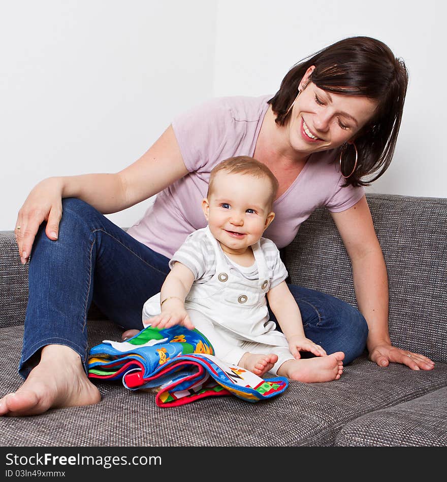 Young baby girl with cute dress and mother playing on the couch. Young baby girl with cute dress and mother playing on the couch.