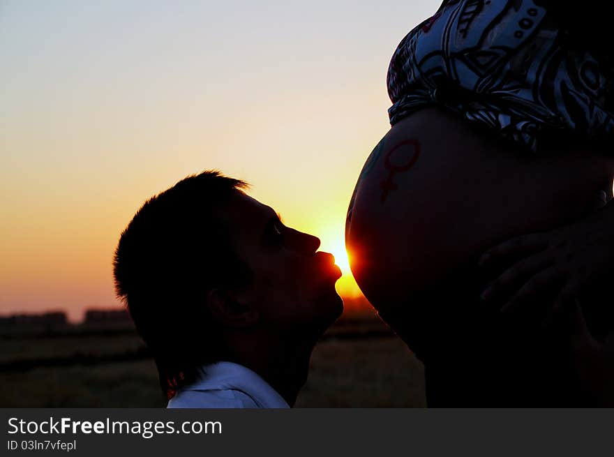 The husband kisses the pregnant wife on a stomach. The husband kisses the pregnant wife on a stomach