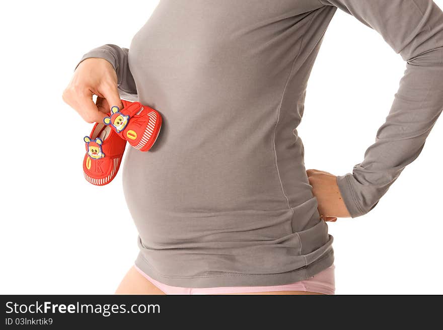 Pregnant woman is holding little shoes