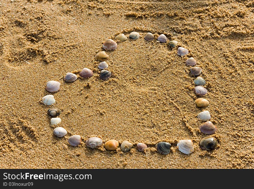 Shell on the sand putten to the love symbol heart. Shell on the sand putten to the love symbol heart