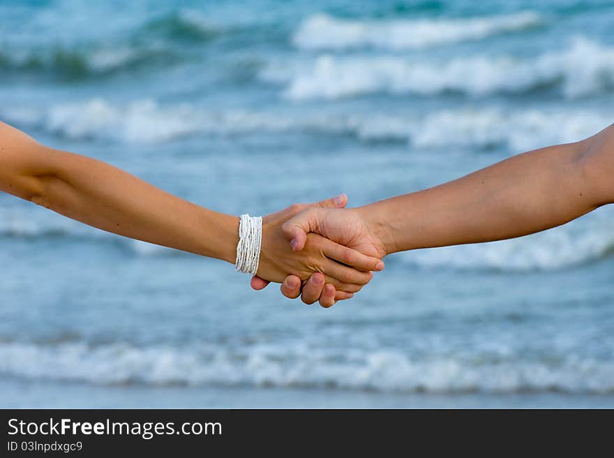 Man s and woman s hand in love on the ocean