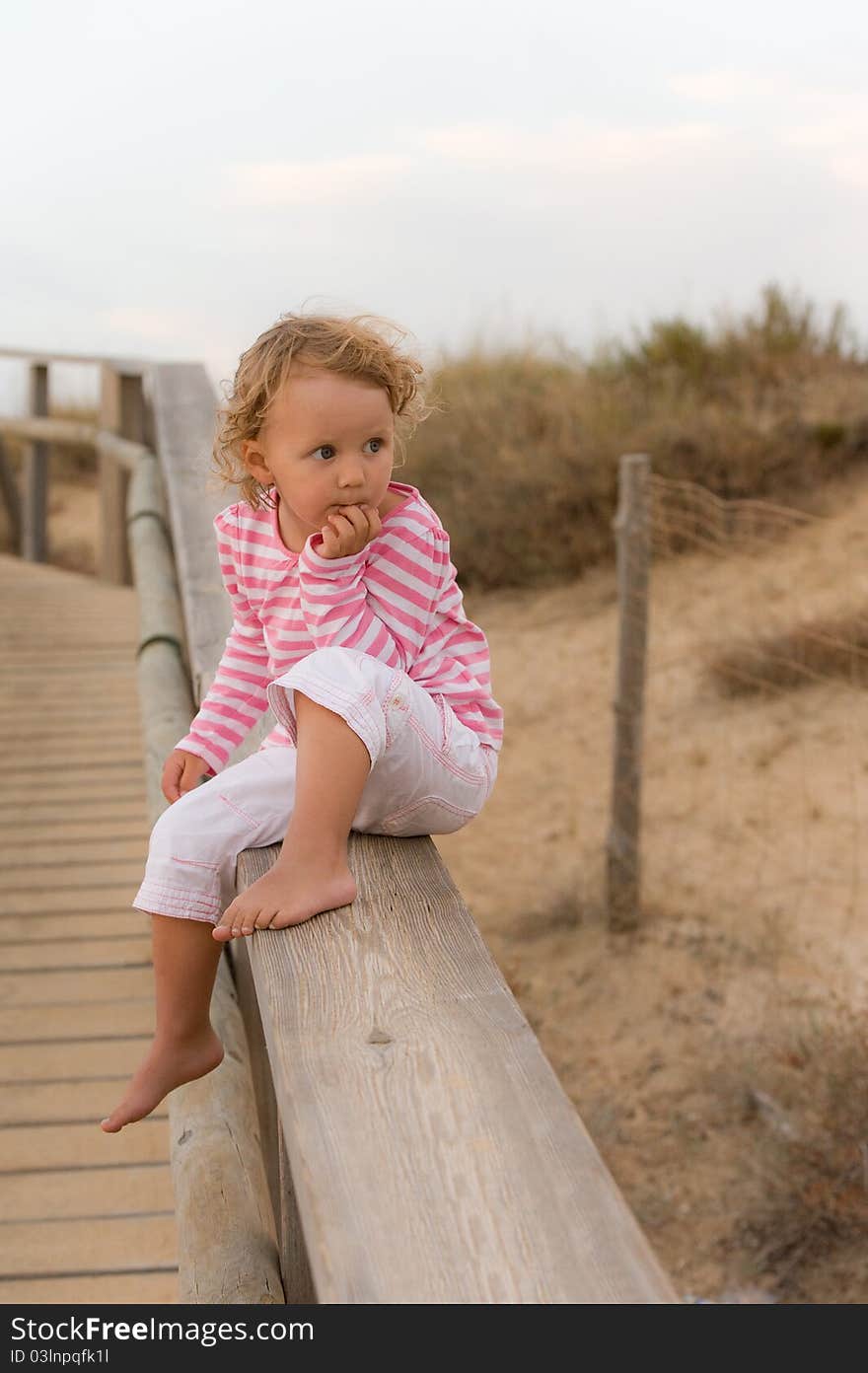 Baby Is Seatting On The Bridge And Looking Ocean