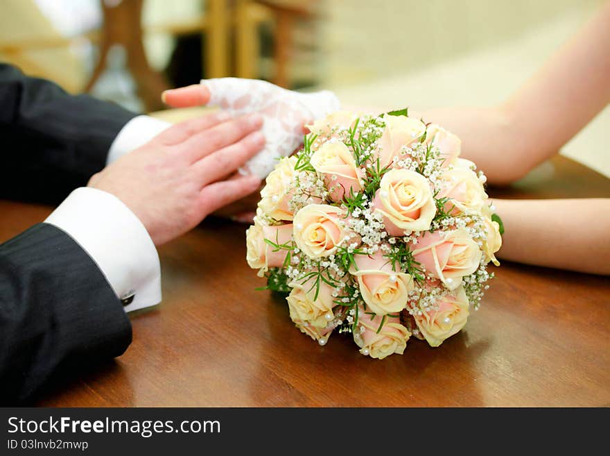 Newly-married couple sits at a table in cafe and on a table the bouquet of the bride lies. Newly-married couple sits at a table in cafe and on a table the bouquet of the bride lies