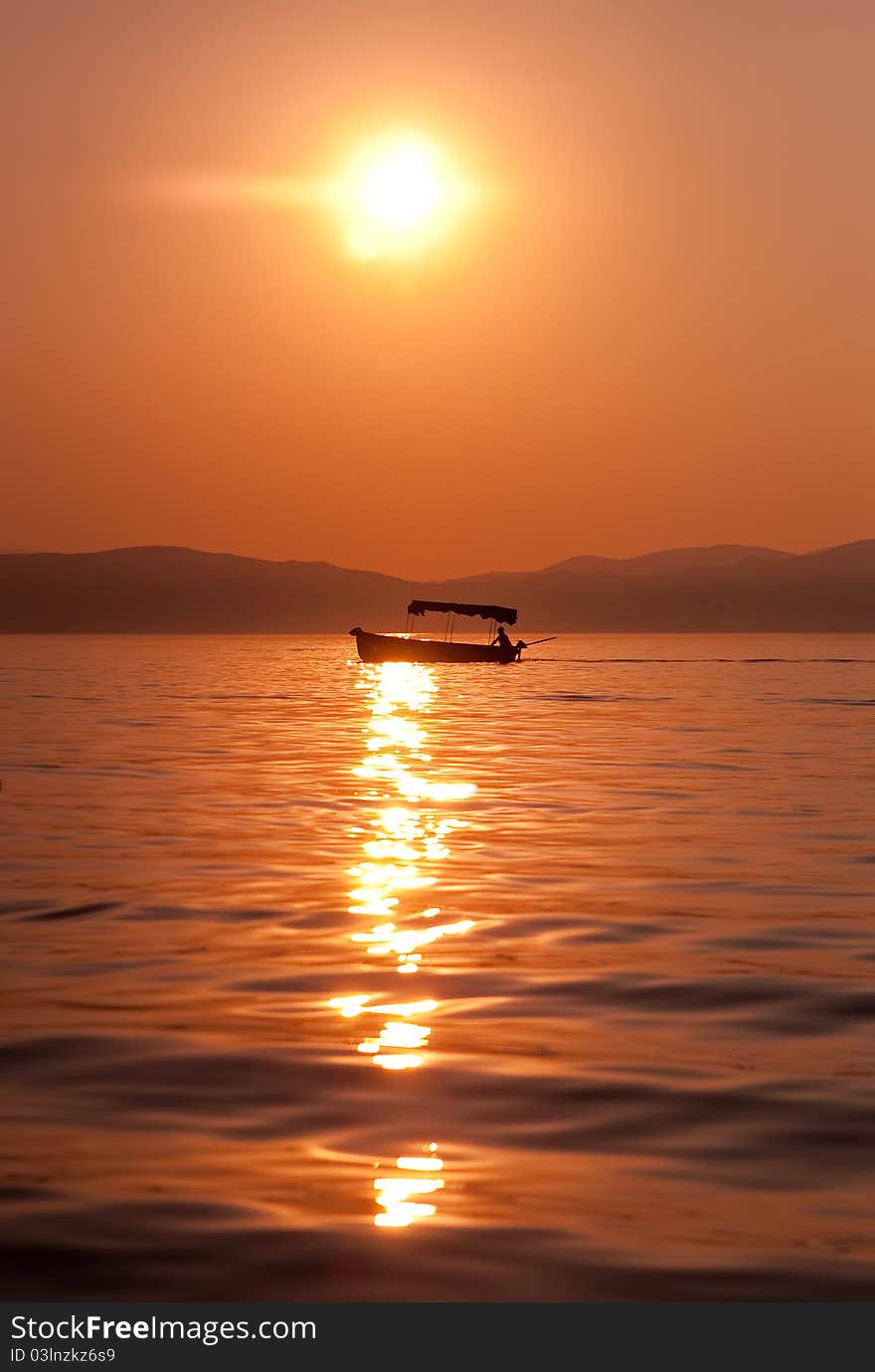 Fishermen crossing a lake at sunset in a boat