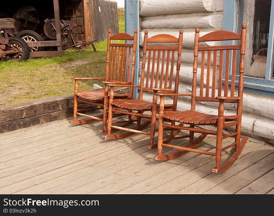 Three rocking chairs on a porch ready for someone to relax in