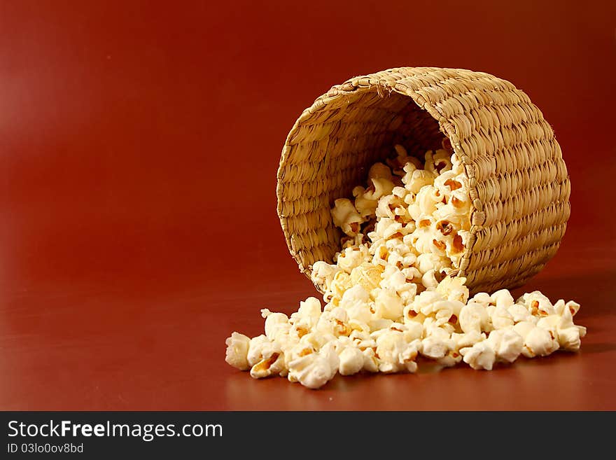 Spread popcorn on red background with basket