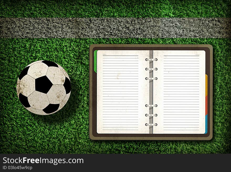 Football and blank notebook on Green Grass background