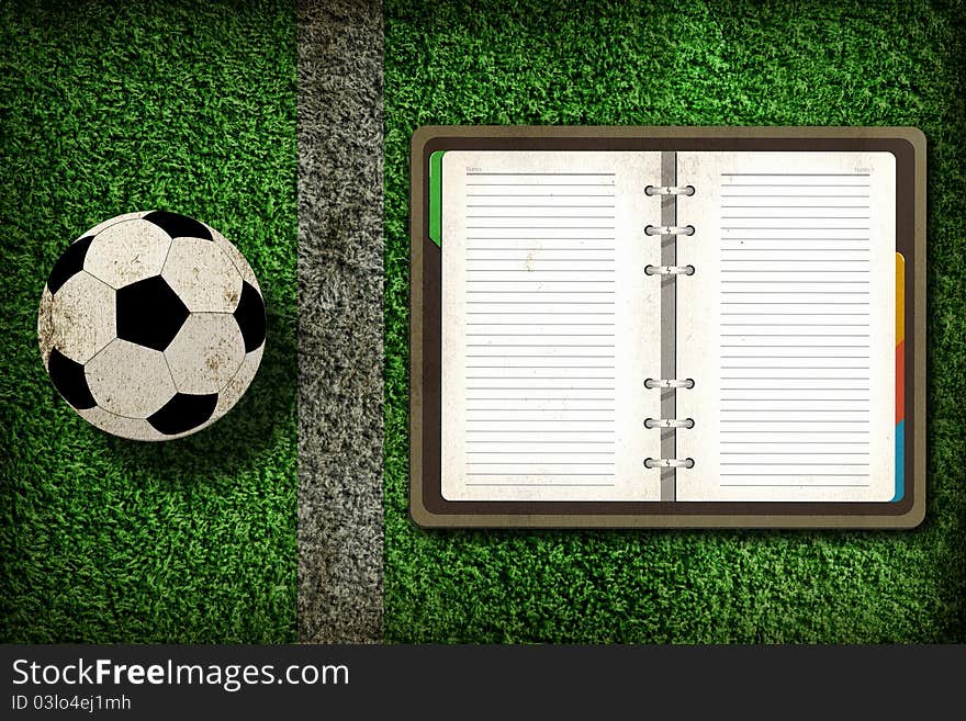 Football and blank notebook on Green Grass background